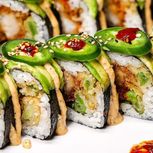 Himiko Sushi roll with avocado, tempura, jalapeno slices, sesame seeds, and spicy sauce.