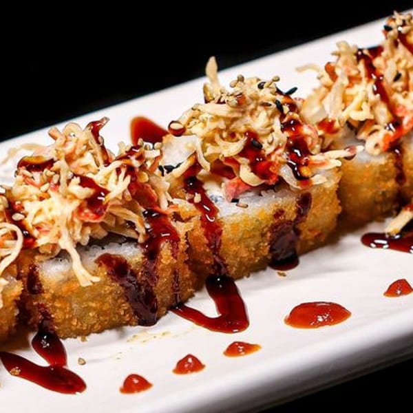 Three Himiko Sushi rolls, deep-fried and topped with shredded crab, sauce, and sesame seeds.
